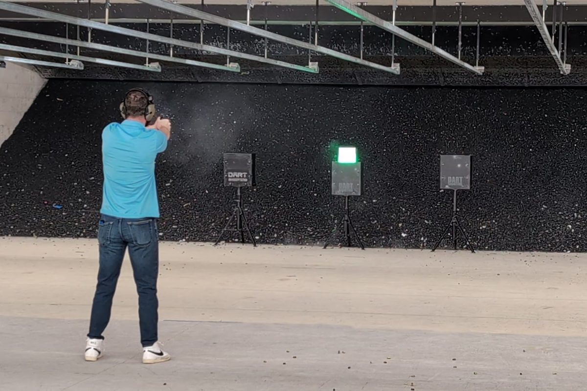 A shooter engaging a lit DART target from the firing line of a covered range bay